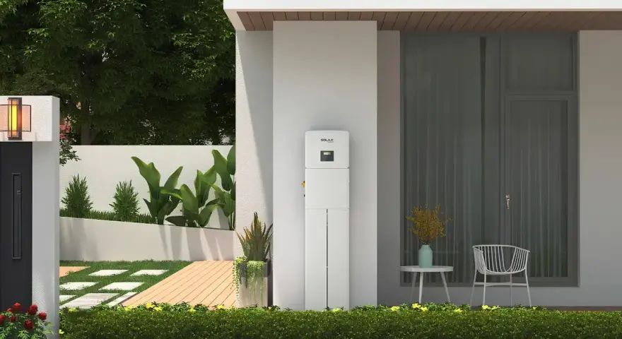 Biały magazyn energii 5 kW, stojący przy nowoczesnym domu, z zielenią i tarasem. Zastanawiasz się, na ile wystarczy taki magazyn energii?