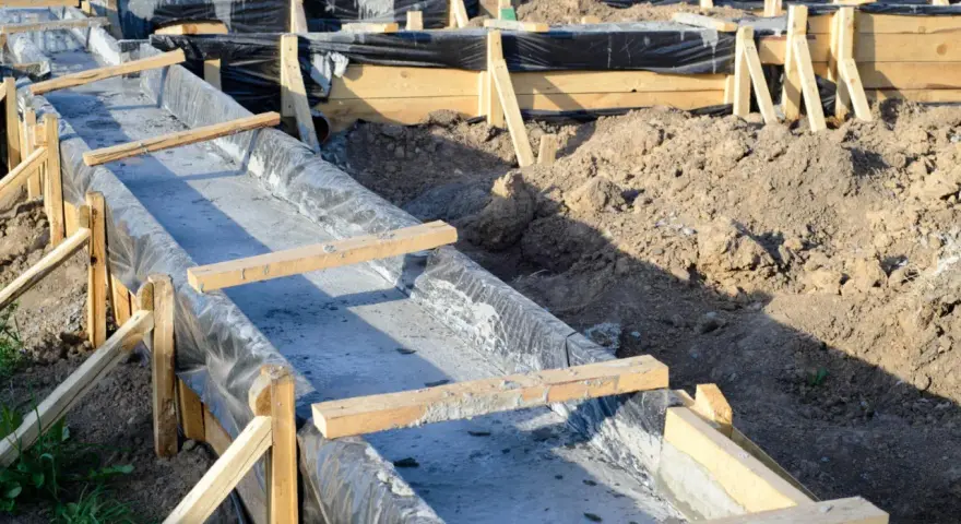 Budowa fundamentów: betonowe ławy w drewnianym szalunku, wyłożone czarną folią.