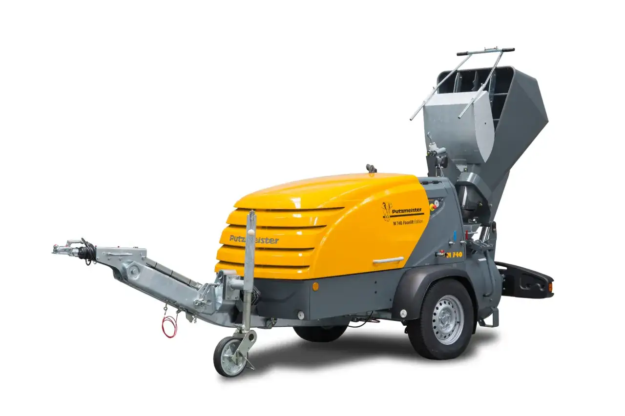 Żółto-szary miksokret Putzmeister M 740 Facelift Edition na przyczepie, gotowy do pracy na budowie.