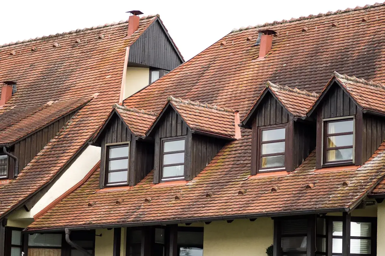 Dachówki dachowe z kilkoma lukarnami, każda z drewnianą obudową i oknem.