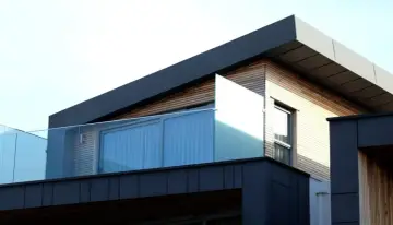 Nowoczesny budynek z drewnianą elewacją i szklanymi balustradami. Solidna hydroizolacja dachu zapewnia ochronę przed wilgociącią.