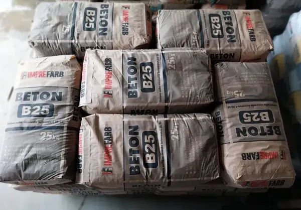 Sztaplowane worki z betonem B25, każdy po 25 kg. Wiedząc, ile waży kubik betonu, można oszacować potrzebną ilość materiału.
