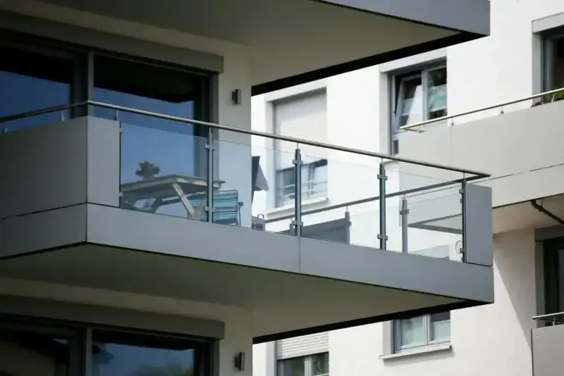 Nowoczesna loggia z przeszklonymi balustradami, na której stoi stolik z krzesłami.