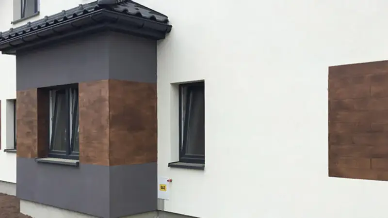 Nowoczesna elewacja z elementami imitującymi drewno, wykonana z tynków cementowo wapiennych.