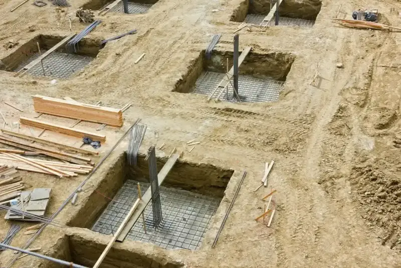 Wykopy pod fundamenty, zbrojenie i drewno budowlane. Trwa podbijanie fundamentów pod przyszły budynek.