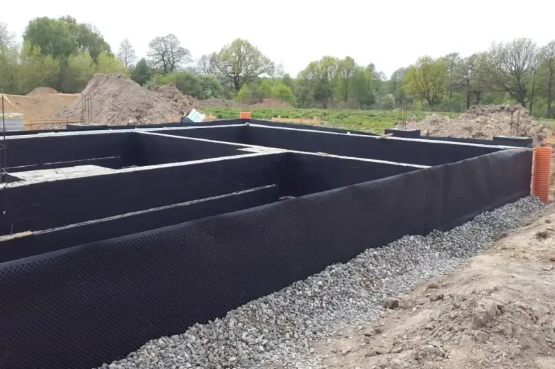 Fundament gotowy do izolacji. Czarna membrana z wypustkami, czyli izoplast b, chroni ściany przed wilgocią.